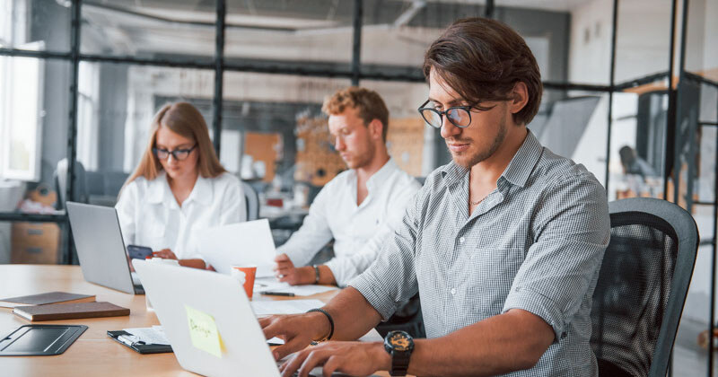 guy-glasses-front-his-employees-young-business-people-formal-clothes-working-office