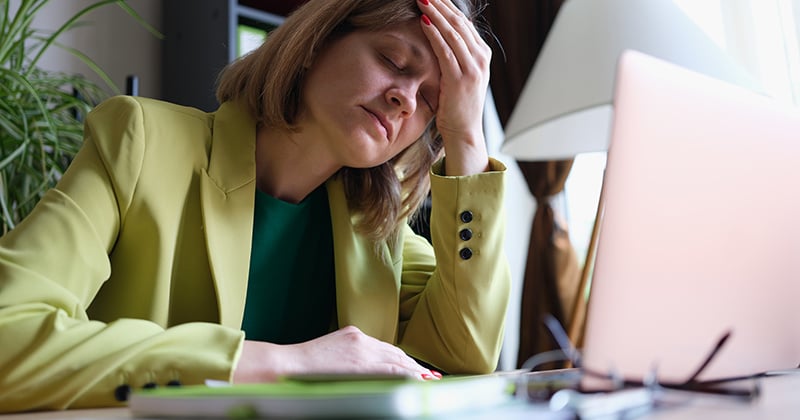 portrait-overworked-woman-sitting-office-touching-forehead-with-hand-stressful