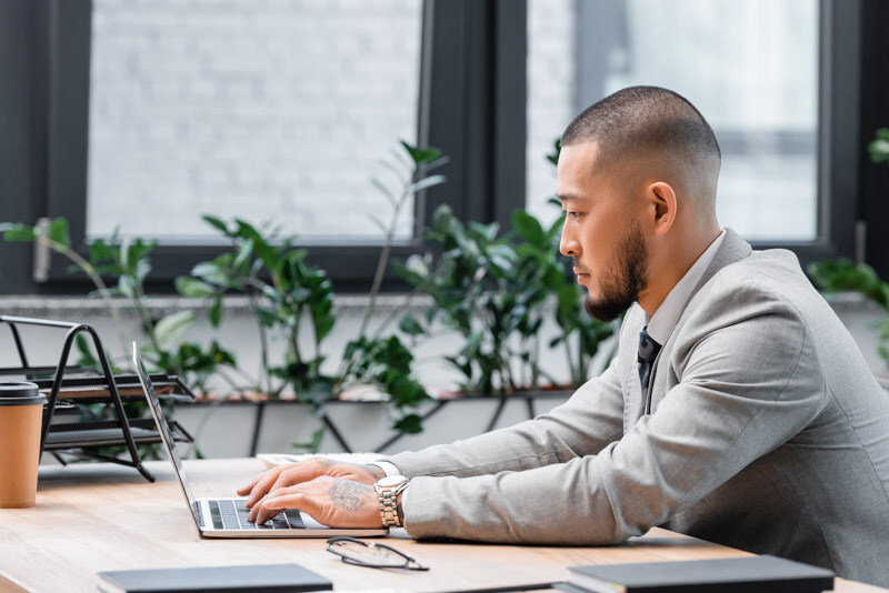 side-view-bearded-asian-businessman-working-laptop-office