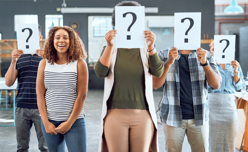 theres-no-questioning-my-position-this-company-portrait-young-businesswoman-standing-amongst-her-colleagues-holding-up-placards-with-question-marks-office-2